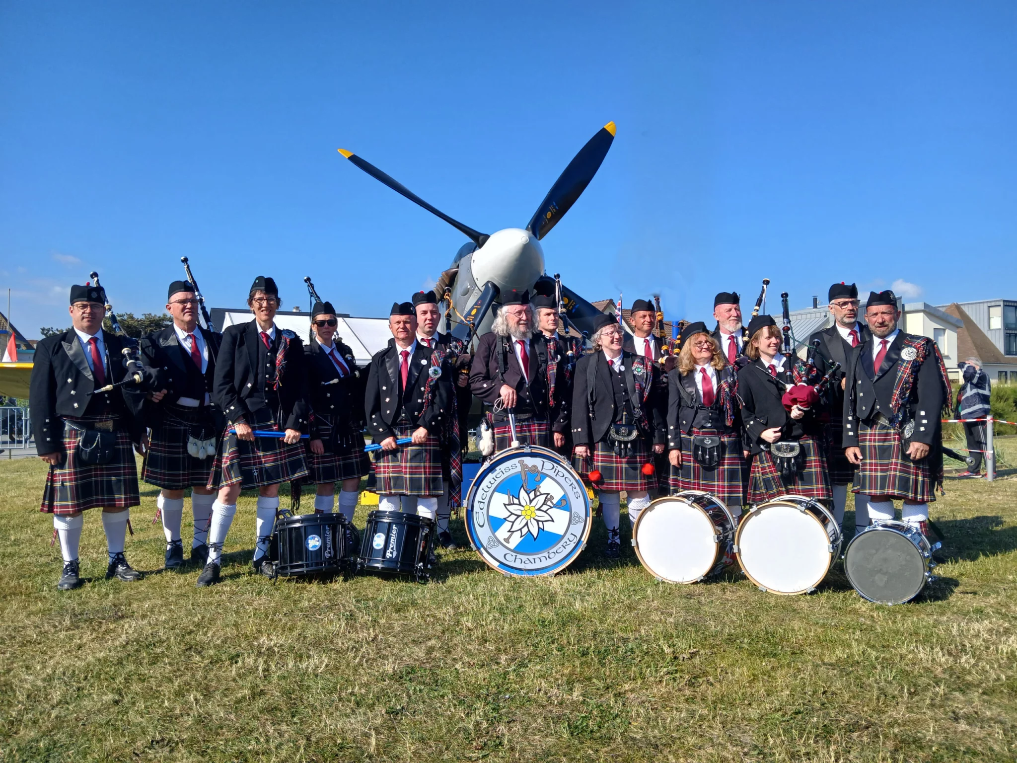 Musiciens en kilt et tambours devant un avion à hélice.